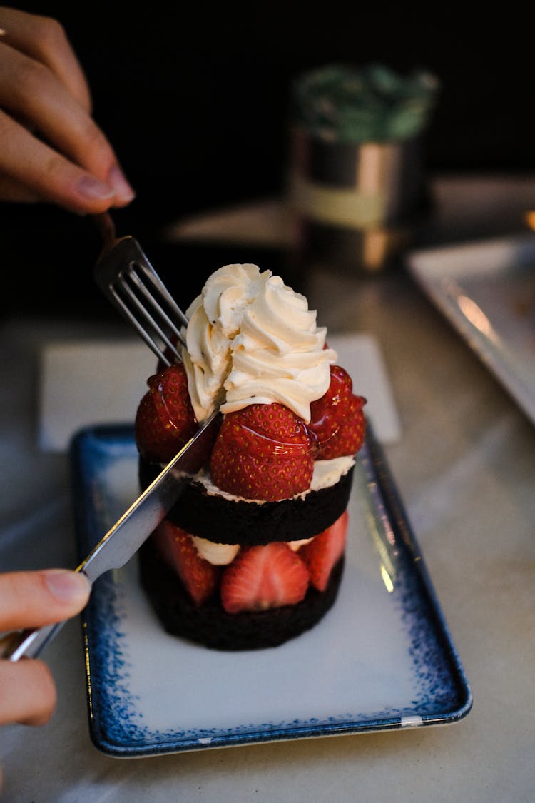 Person Eating Chocolate Cake With Fruits And Cream