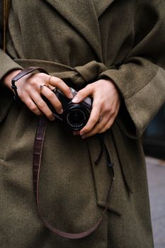 Stylish individual in a coat holding a camera in Istanbul's urban setting.
