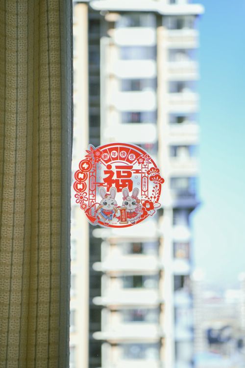 Free Red decorative sticker on window contrasting with a modern high-rise building, blending tradition with urban life. Stock Photo