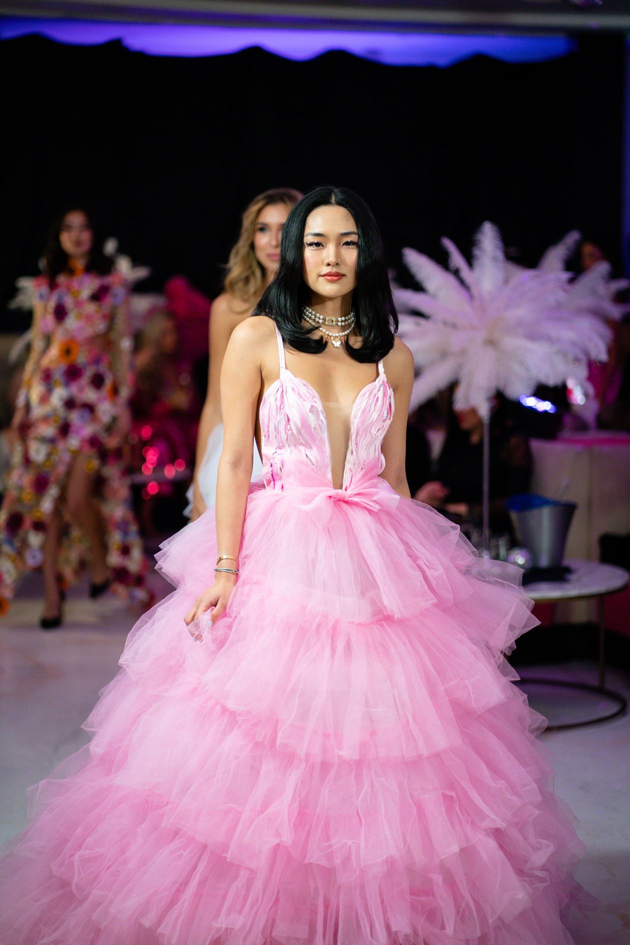 Model walking a runway in a bright pink tiered tulle ball gown