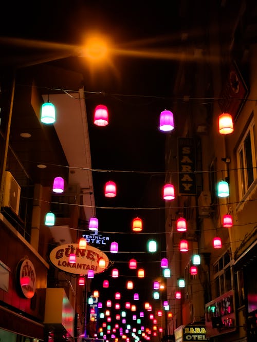 Colorful Lights Hanging above a Street and between Buildings in City 