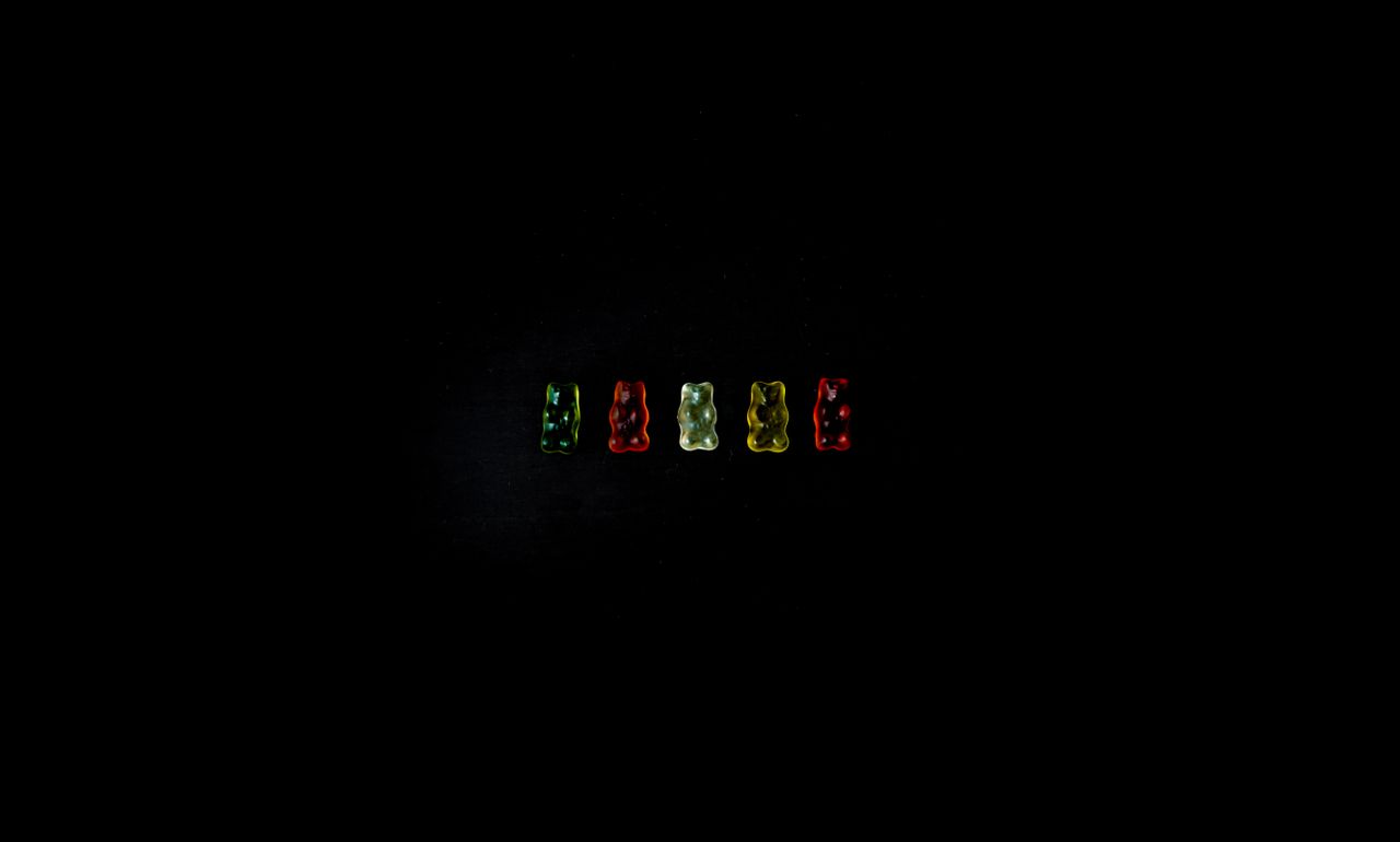 a studio shot of colorful gummy bears aligned on a black background