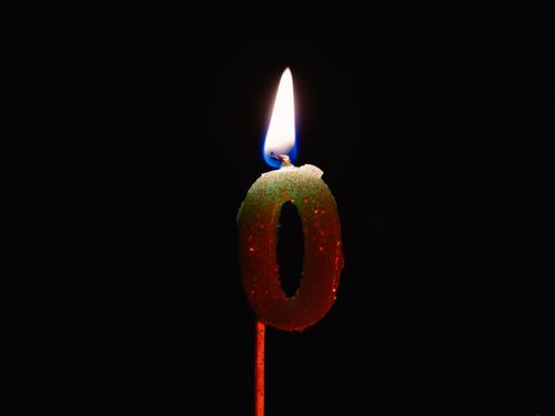 Free Close-up of a number zero candle burning against a dark background. Stock Photo