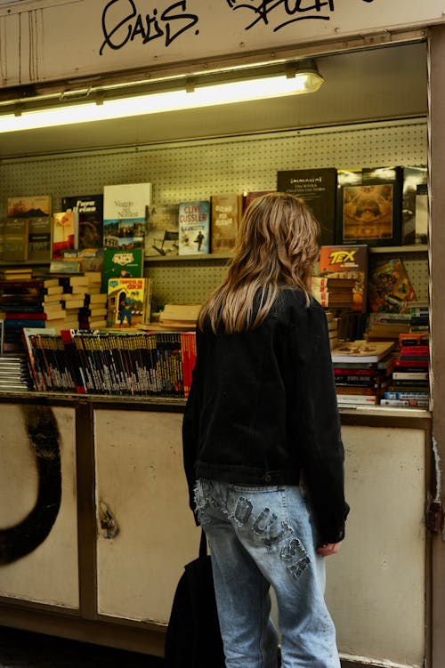 Person in Black Long Sleeve Shirt Standing Near Counter of a Bookstore