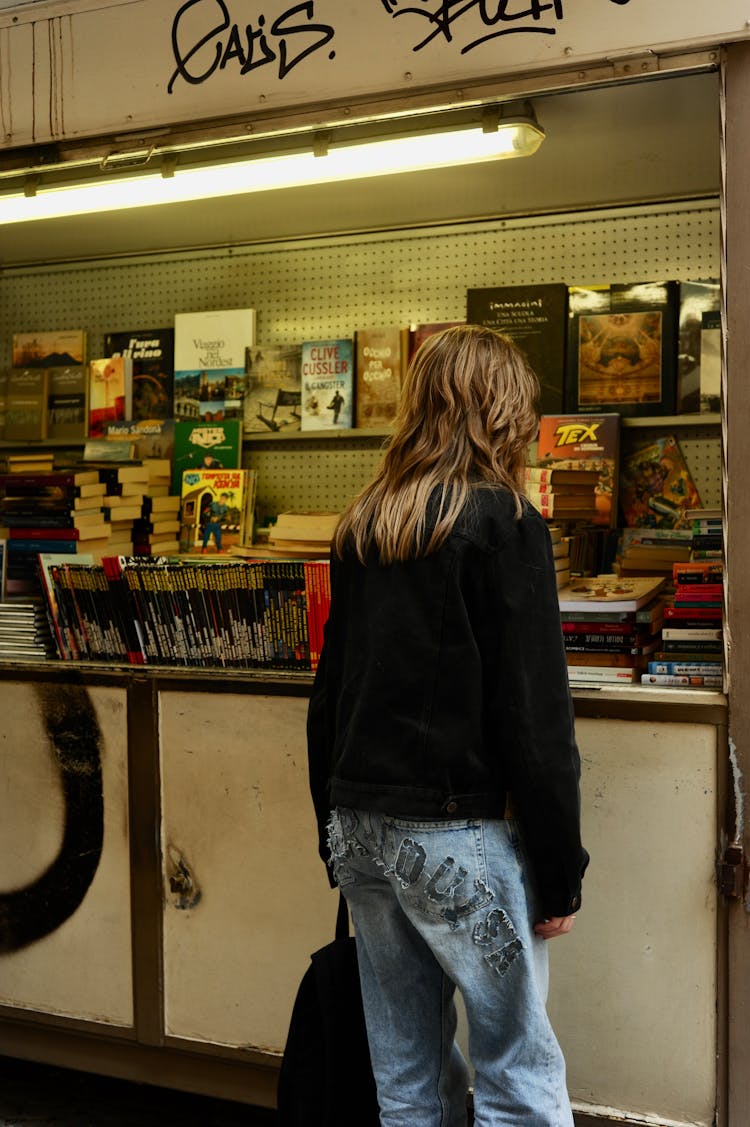 Person In Black Long Sleeve Shirt Standing Near Counter Of A Bookstore