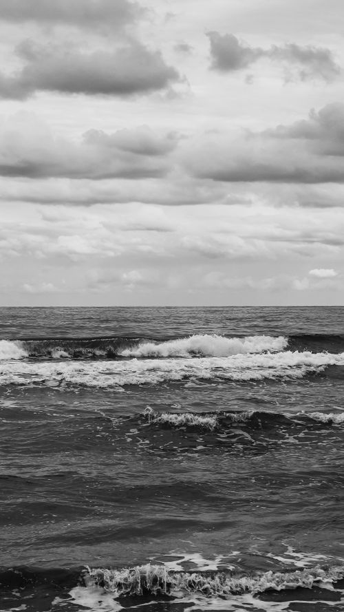 Free A dramatic black and white view of waves crashing on the Mersin coastline under cloudy skies. Stock Photo