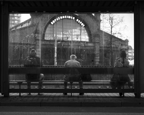 Grayscale Photo of People at the Waiting Shed
