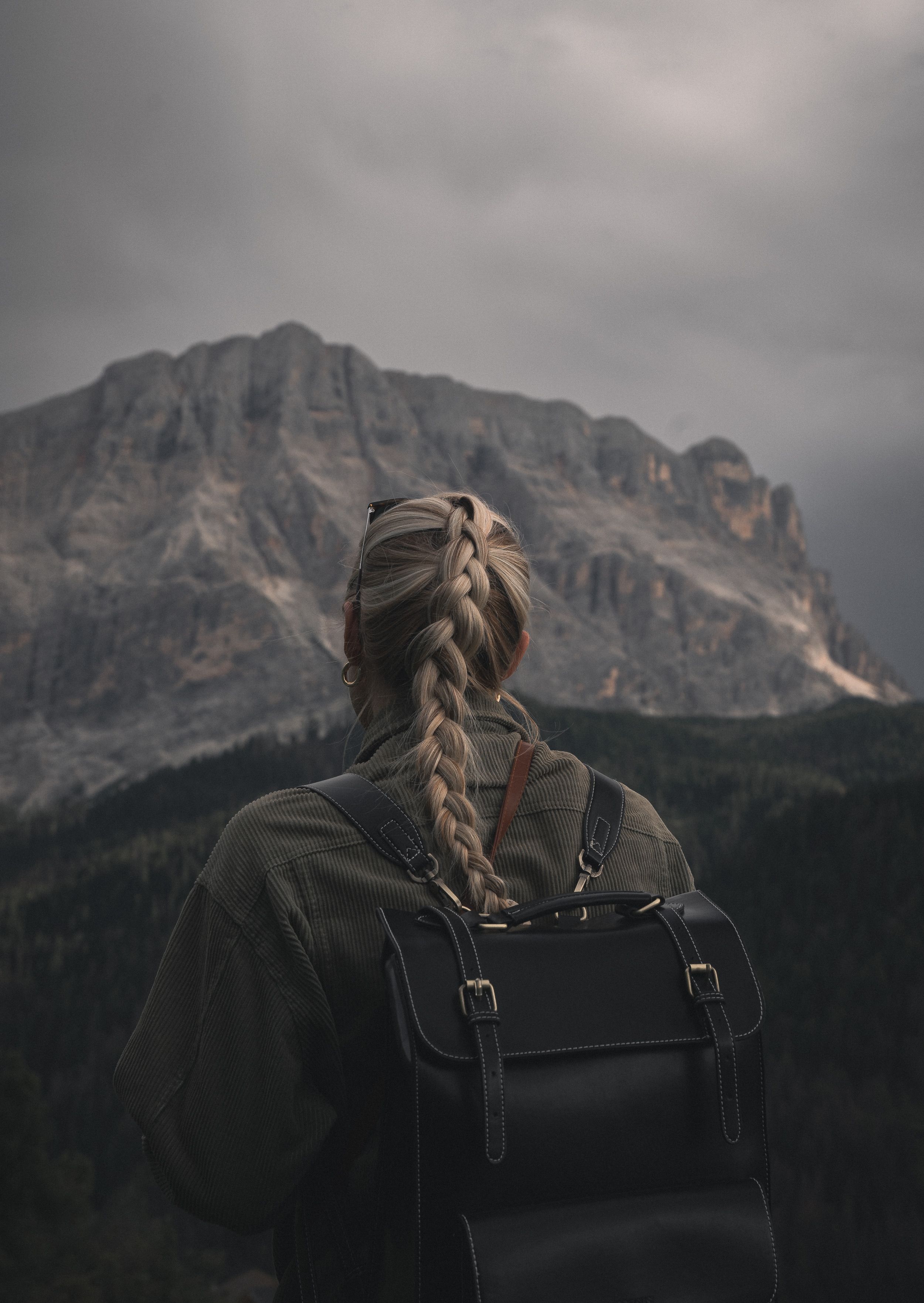 Woman hiker with backpack looking out over a mountain vista on a sunny day
