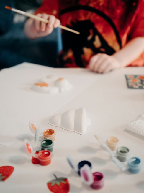 Young child painting with colorful paints on a table, focusing on creativity and fun.
