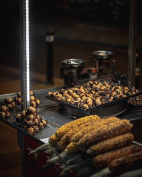 Night shot of a street vendor setup featuring roasted chestnuts and corn, conveying a warm and inviting mood.