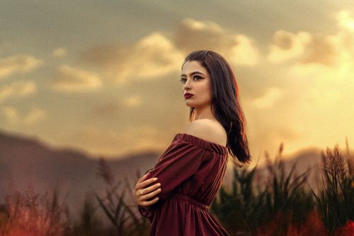 Free Portrait of a woman in an off-shoulder dress during sunset, capturing elegance and beauty. Stock Photo