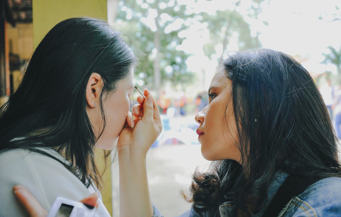 Vrouw Die Make Up Op Vrouw In De Buurt Van Venster