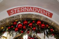 Decorative arch adorned with red Christmas baubles and greenery, ideal for festive settings.