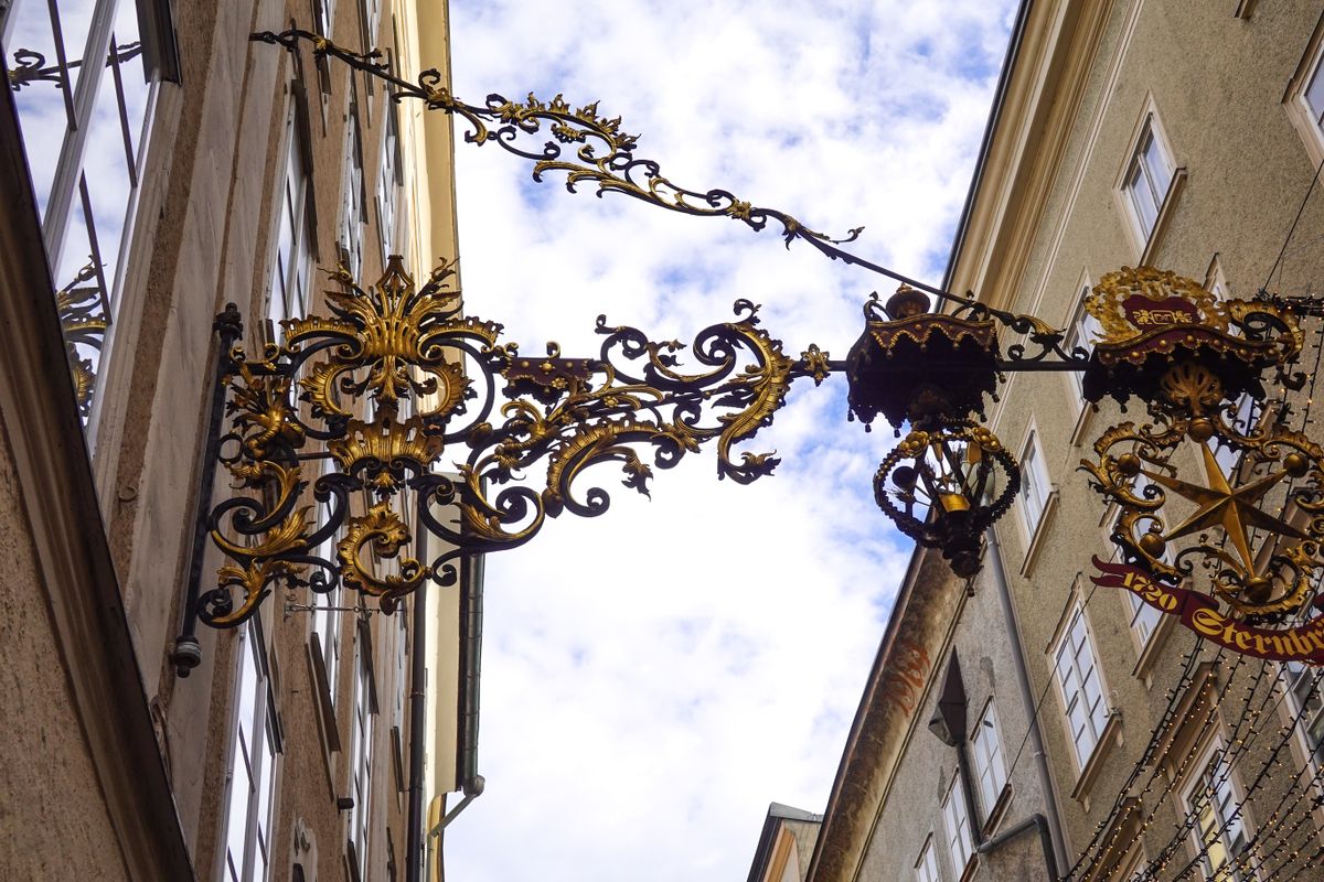 Wrought iron shop signs hanging above a street in Salzburg
