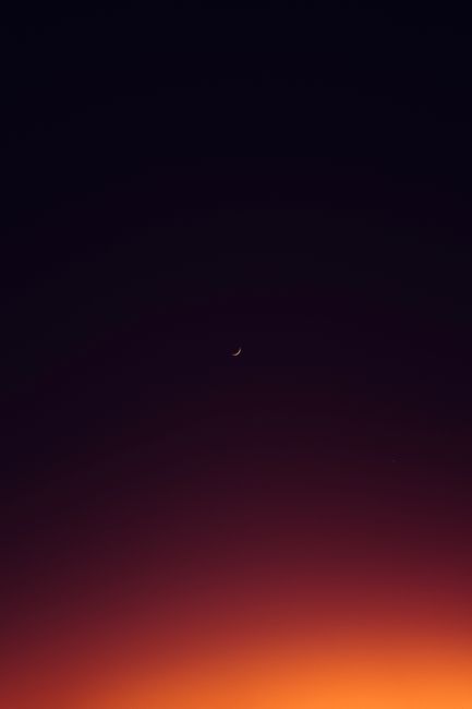 Crescent moon against a colorful dusk sky, capturing twilight magic.