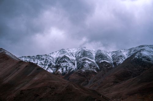 Free A breathtaking view of snow-covered mountains against a dramatic overcast sky. Stock Photo