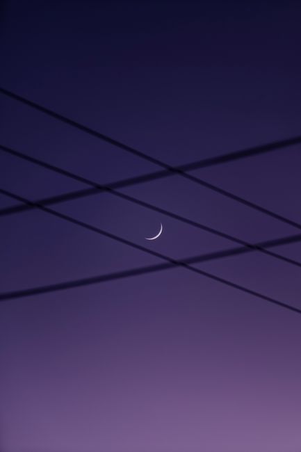 Captivating crescent moon amid silhouetted cables against a serene night sky.