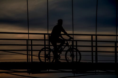 Silhouette of a Cyclist on a Bridge at Dusk 