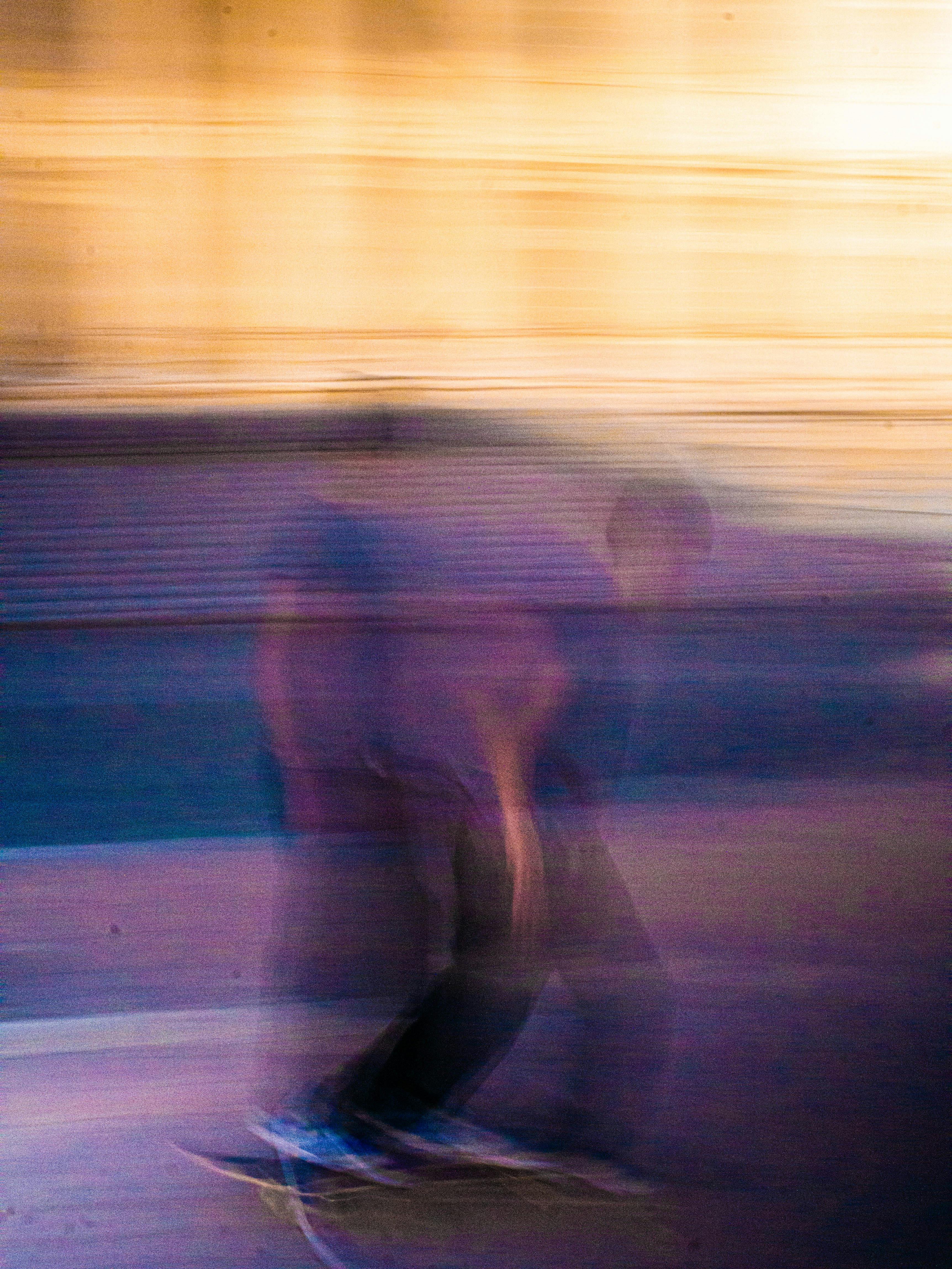 Artistic motion blur captures a skateboarder in mid-action. Abstract and colorful.