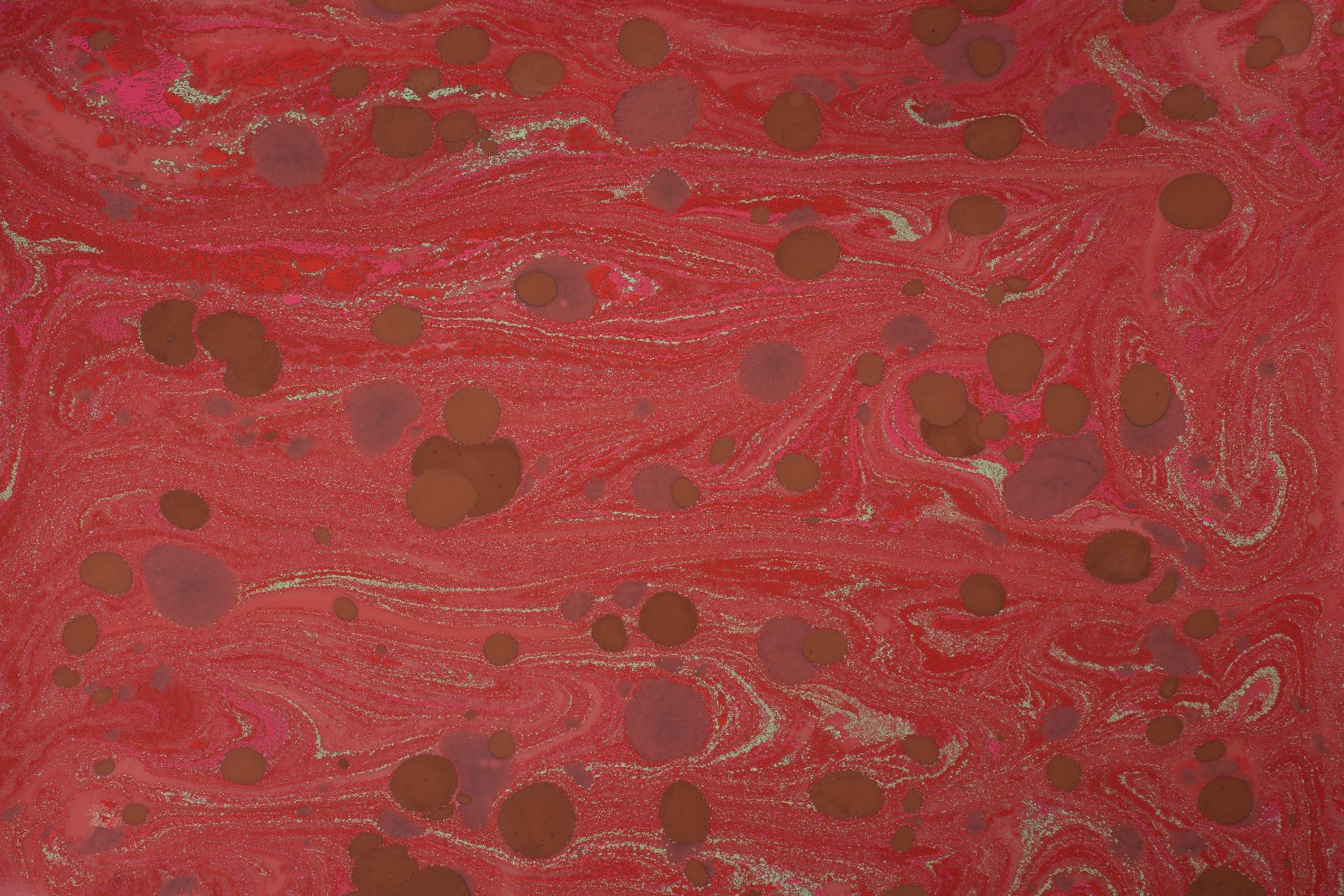 Dynamic red marbled texture with swirling patterns and organic shapes for creative design use.