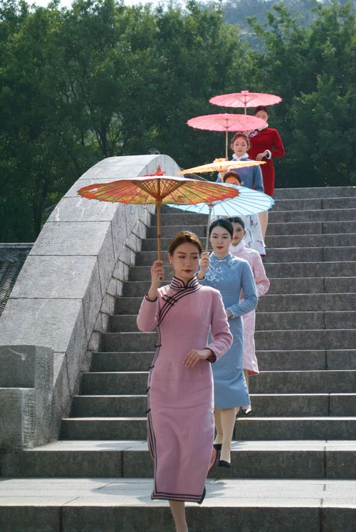 Free Group of Asian women in traditional attire walking with umbrellas on a stone bridge. Stock Photo