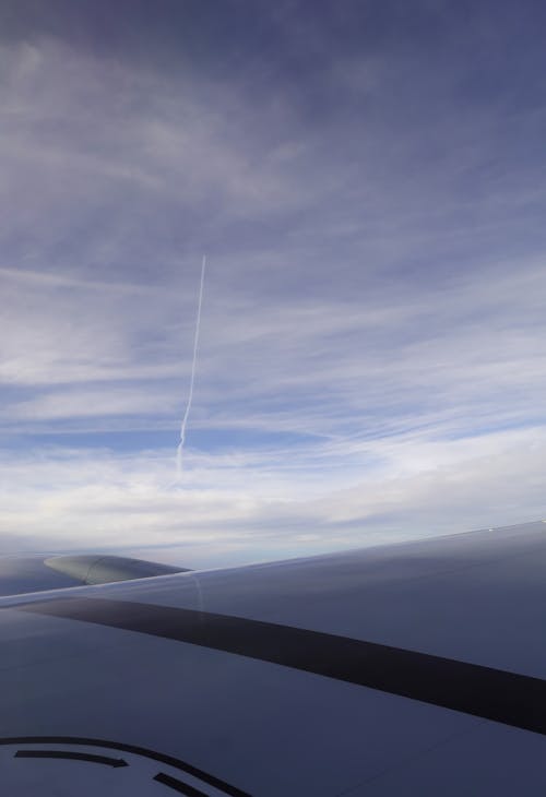 Airplane Wings against Blue Sky with Clouds