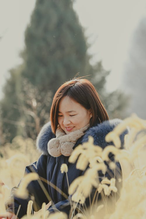 Woman in Warm Clothing Standing on a Field and Smiling 