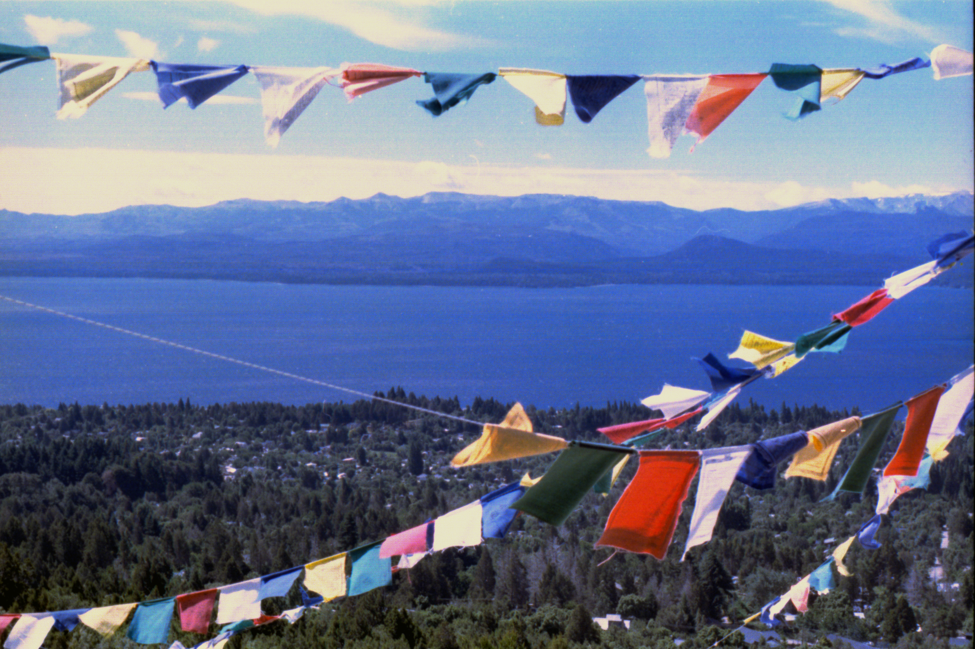 Vibrant prayer flags fluttering over a stunning lake view surrounded by mountains.