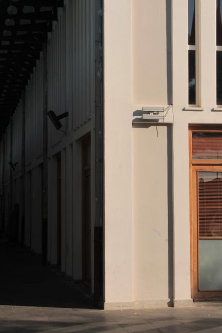 A minimalist urban architecture scene highlighting shadows and symmetry on building facades.