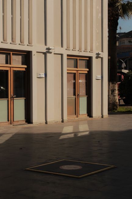Sunlit urban building exterior with wooden doors and modern facade.