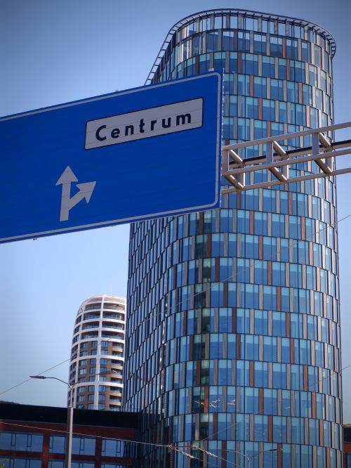 Free A vertical shot of modern skyscrapers in an urban area with a road sign pointing to Centrum. Stock Photo