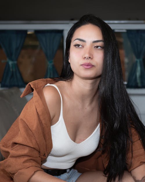 Young Woman in a White Top and Shirt Sitting and Looking Away 