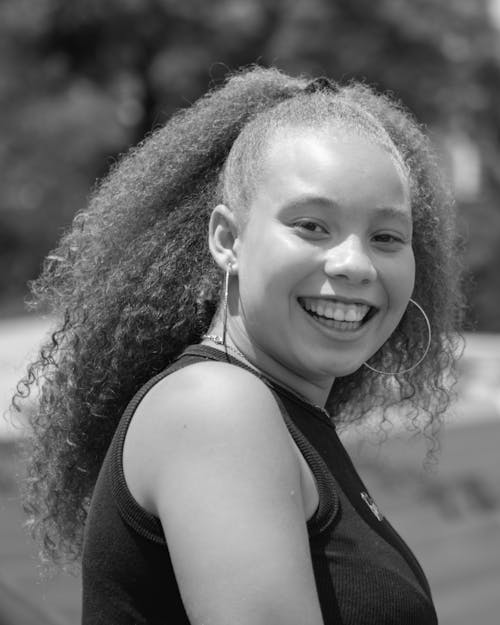 A Grayscale Photo of a Smiling Woman in Black Tank Top