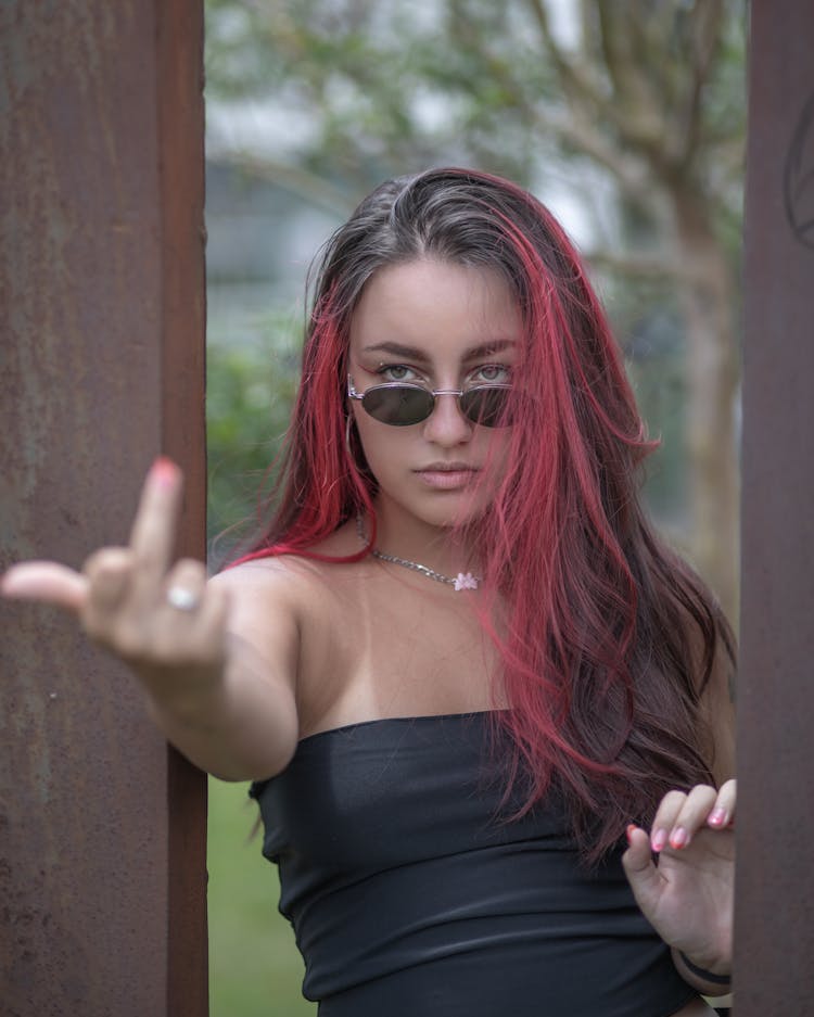 Young Woman With Dyed Hair, Wearing Sunglasses And Showing The Middle Finger