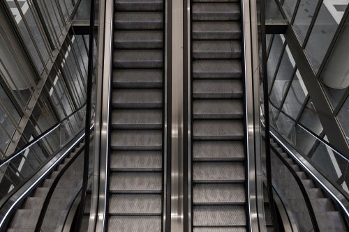 Free Symmetrical view of modern escalators in sleek architectural setting. Stock Photo