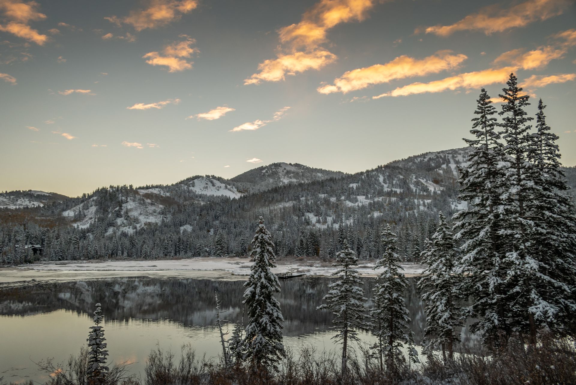 Serene winter landscape of the snowy Wasatch Mountains in Utah reflected in a tranquil lake.