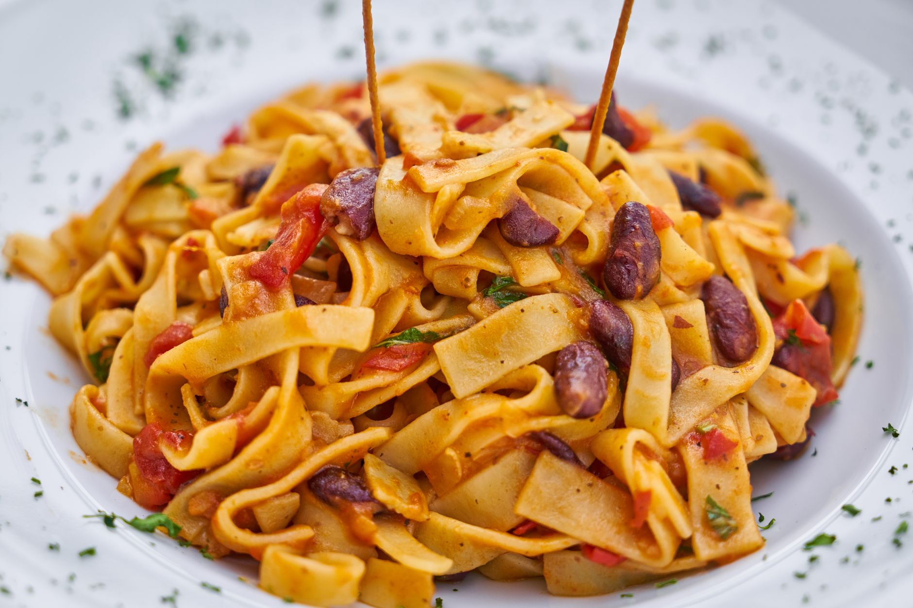Close-up of cooked spaghetti tossed with puttanesca sauce garnished with parsley