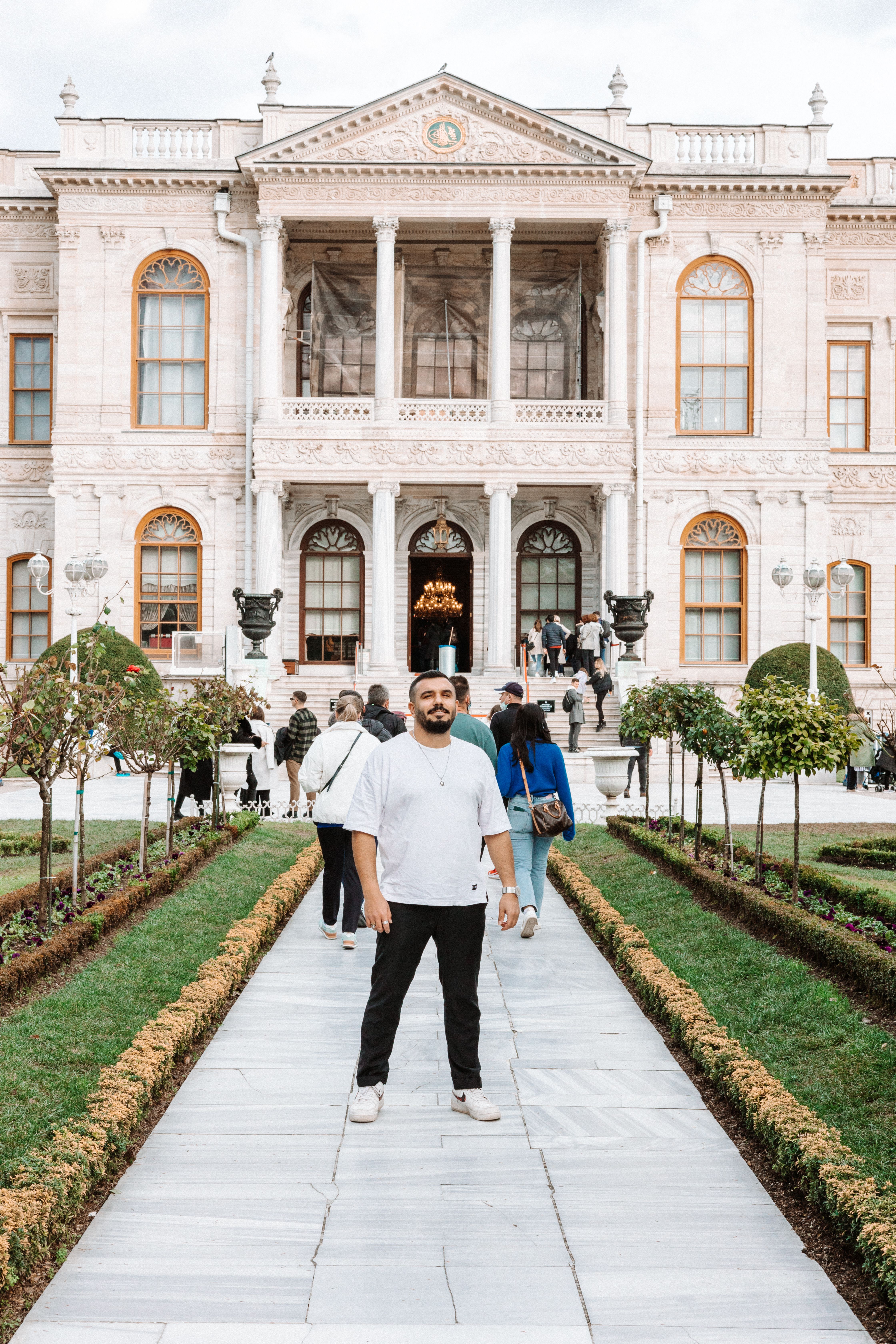 A man stands in front of the historic Dolmabahçe Palace in Istanbul, Turkey on a cloudy day.