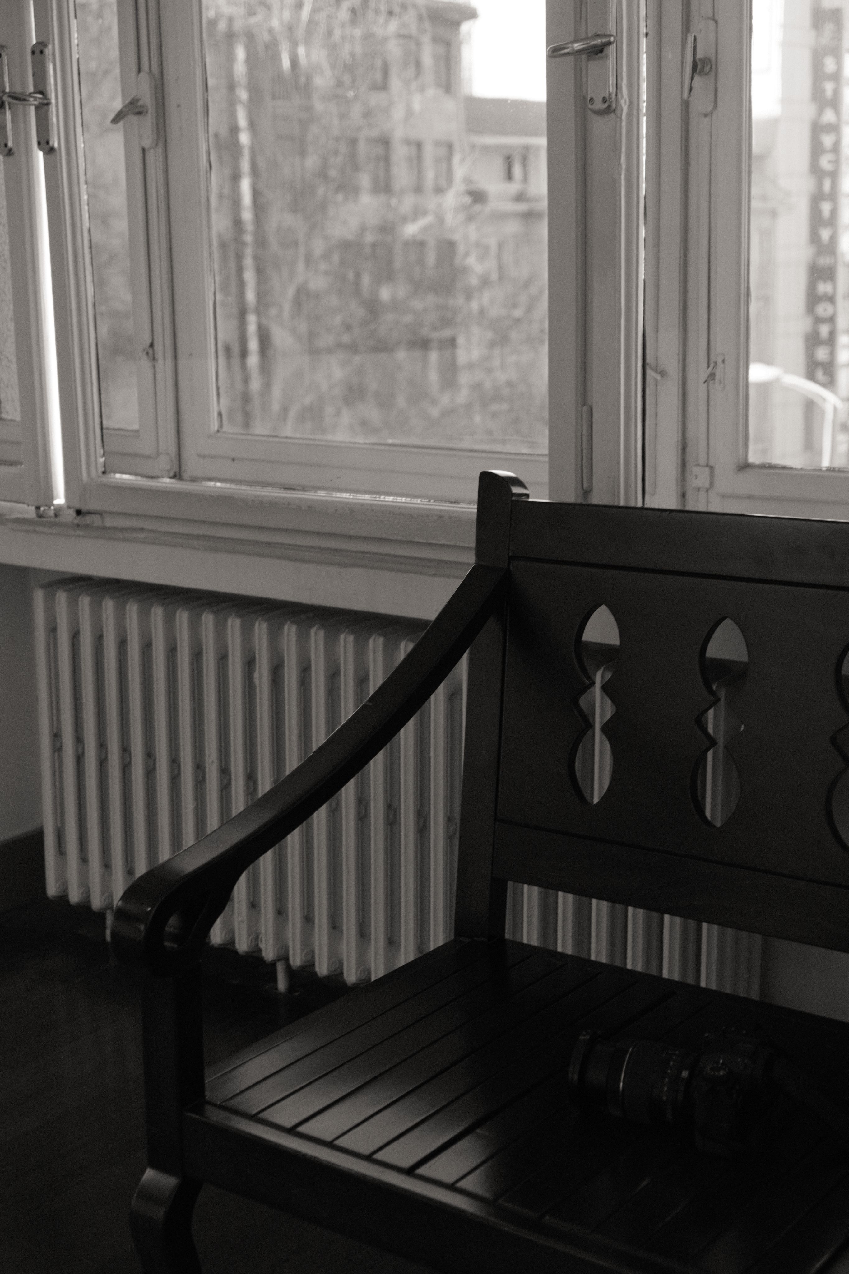 Black wooden bench next to a sunlit windowsill in a classic interior.