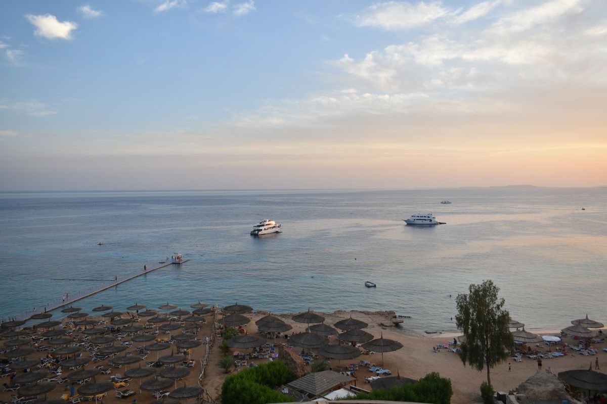Unde te cazezi în Sharm El Sheikh - plaja cu umbrele și bărci la apus