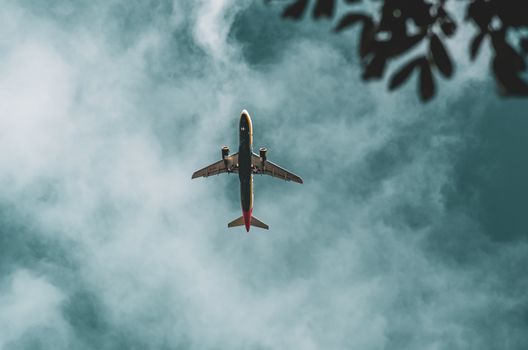 A commercial airplane soaring through a cloudy sky with a moody atmosphere.