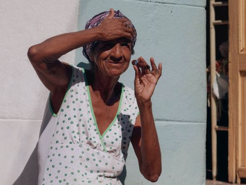 Free Senior woman with headscarf enjoying a cigar outdoors in summer sunlight. Stock Photo