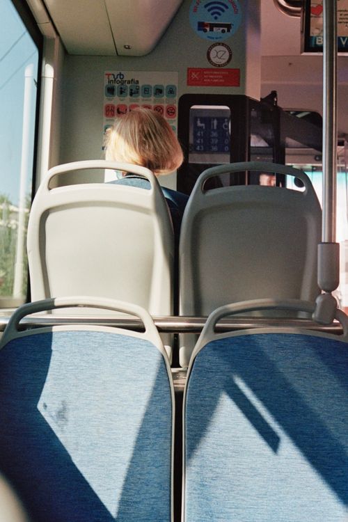 Free View from a bus, showing empty seats and a lone passenger in daylight. Stock Photo