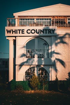 A stylish building exterior showcasing white facade and balcony shadows in warm light.