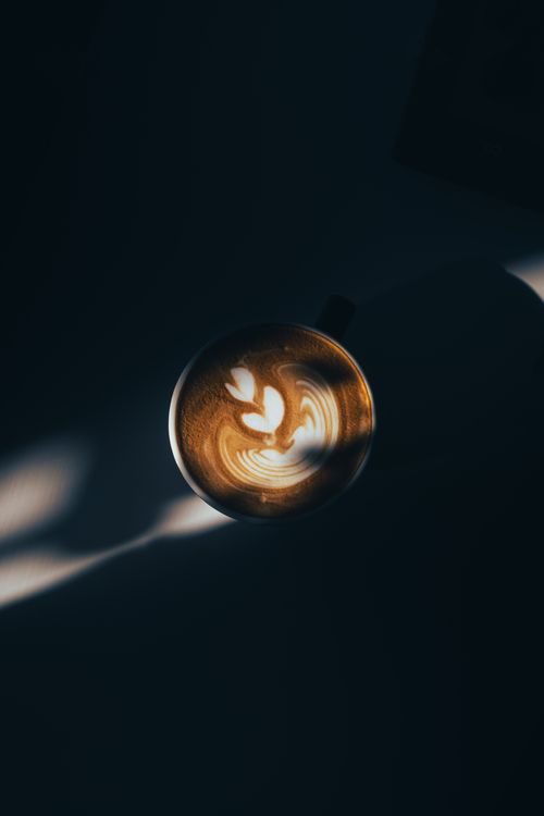 Free Top view of a cup showcasing intricate latte art, bathed in moody shadows. Perfect for coffee lovers. Stock Photo