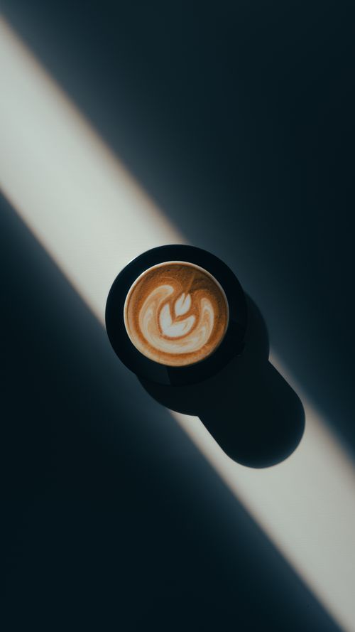 Free Aerial shot of a latte showcasing beautiful foam art in a minimalist setting, highlighting shadows. Stock Photo