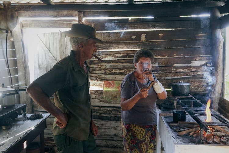 Man And Woman Smoking Cigars In Wooden Shed