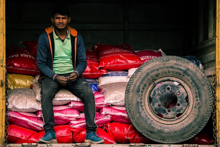 Man Sitting On Bags Near Wheel