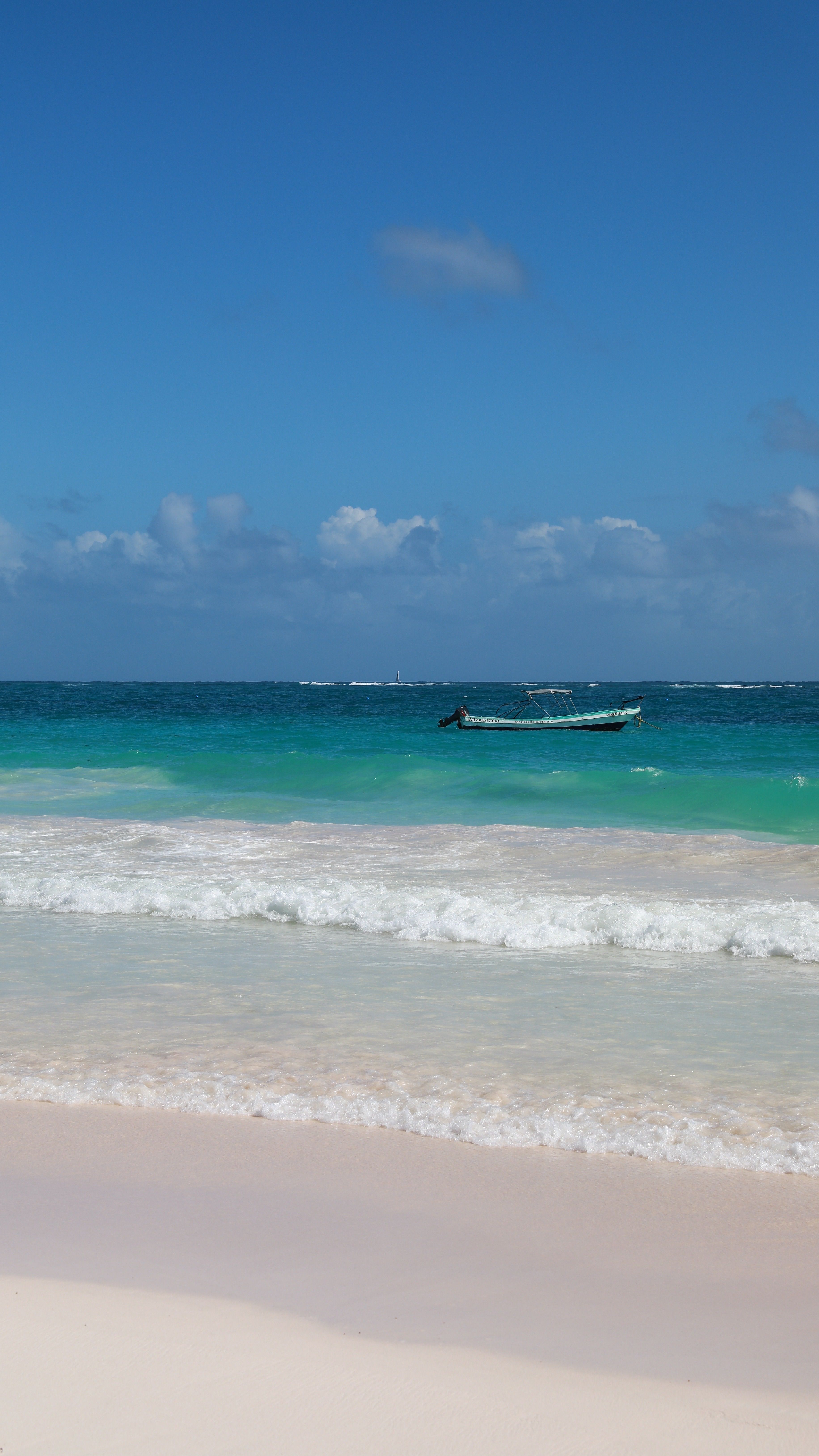 Bateau sur les eaux turquoise de la plage de Tulum au Mexique sous un ciel dégagé