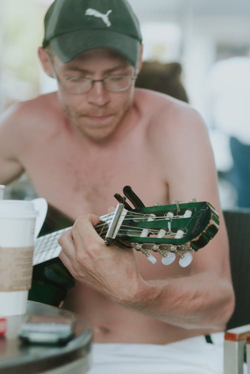 Topless Man Playing an Acoustic Guitar